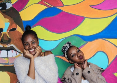 Two girls in the colorful posed on the wall
